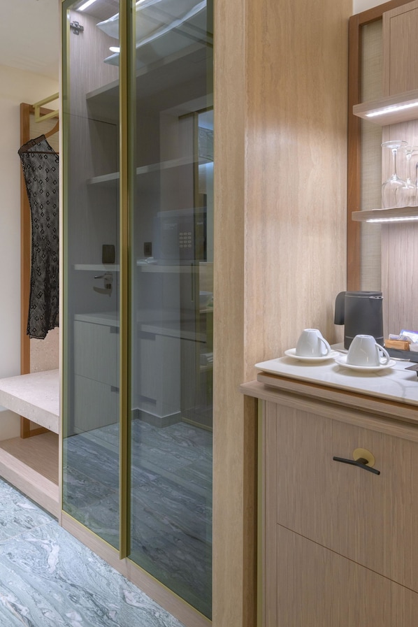 A modern bathroom with a glass shower enclosure, a wooden vanity with a coffee maker, and a shelf with wine glasses. - Elysium Resort & Spa (Rhodes)