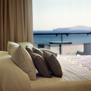 Habitación de hotel con cama, almohadas y vista al mar.