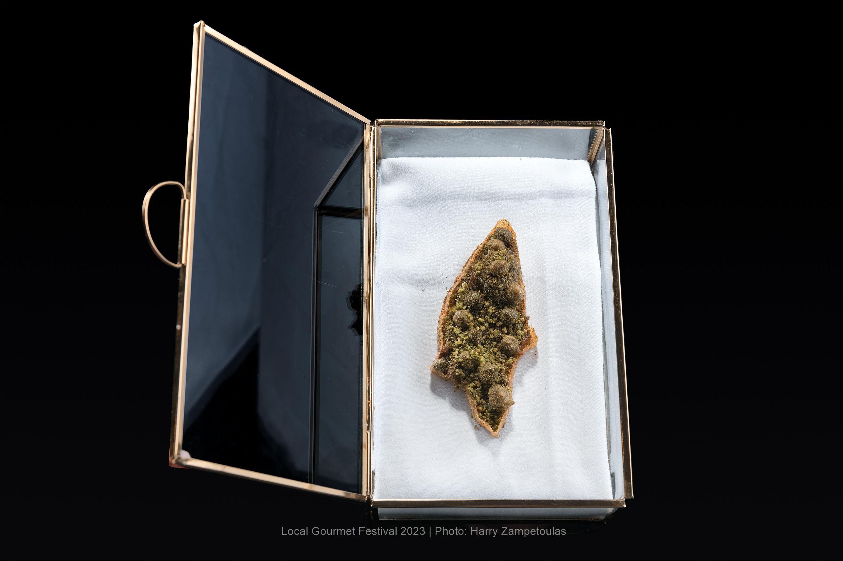 Una vitrina con un objeto triangular sobre un paño blanco.