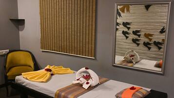 Une chambre d’hôtel comprenant un lit, une chaise, une fenêtre avec des stores, un miroir fixé au mur et une décoration murale représentant des oiseaux.