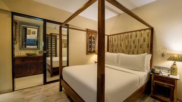 A four-poster bed with a wooden frame, a bedside table with a lamp, and a mirror on the wall.