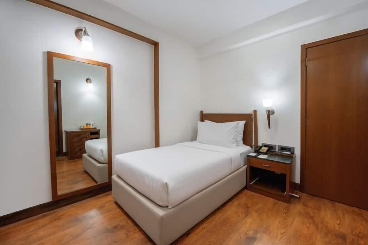 A bedroom with a bed, bedside table, nightstand, mirror, and wardrobe.