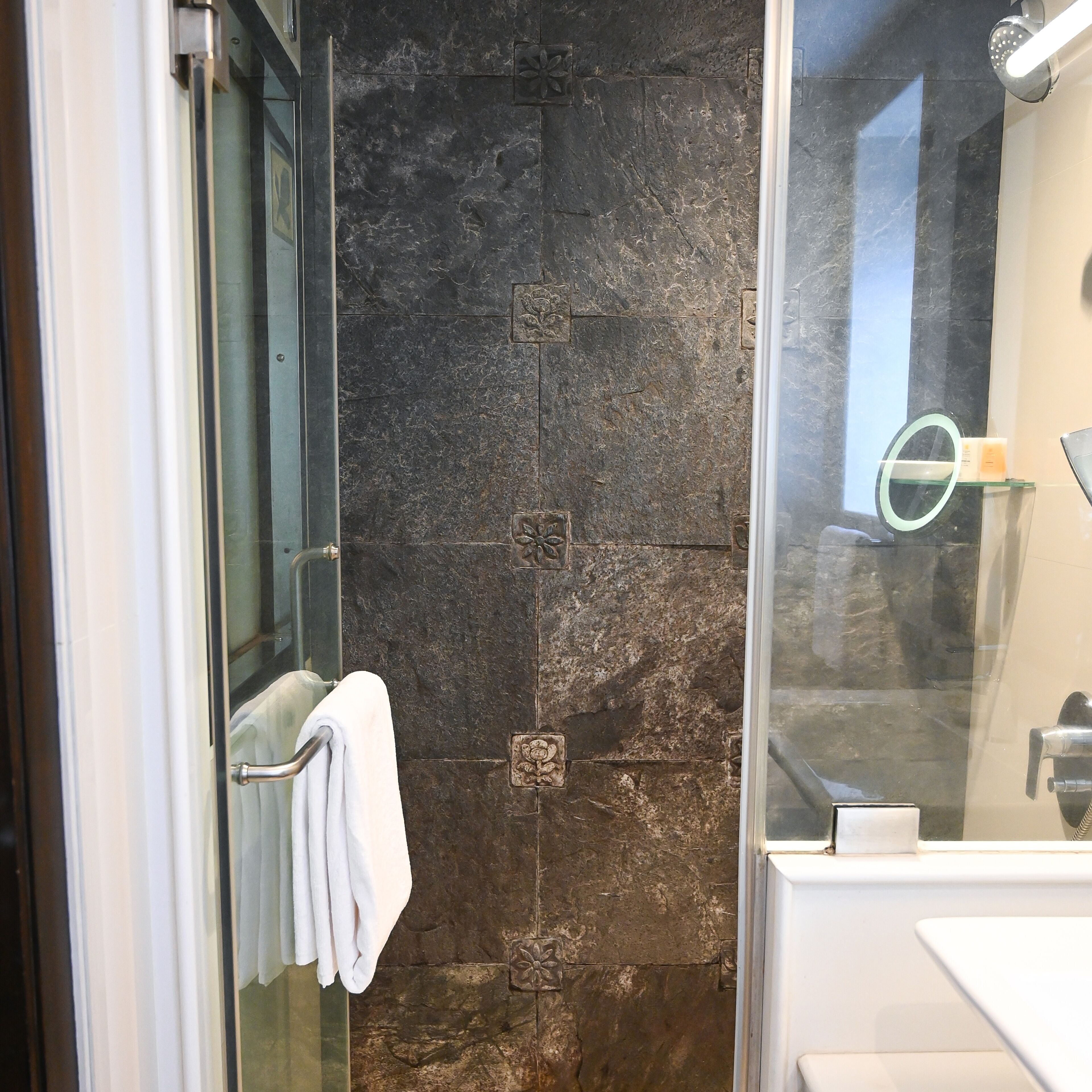 Un baño moderno con cabina de ducha de vidrio, un lavabo blanco y un espejo.