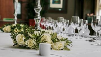 Una mesa dispuesta para un evento formal, con rosas blancas y un centro de mesa con velas.