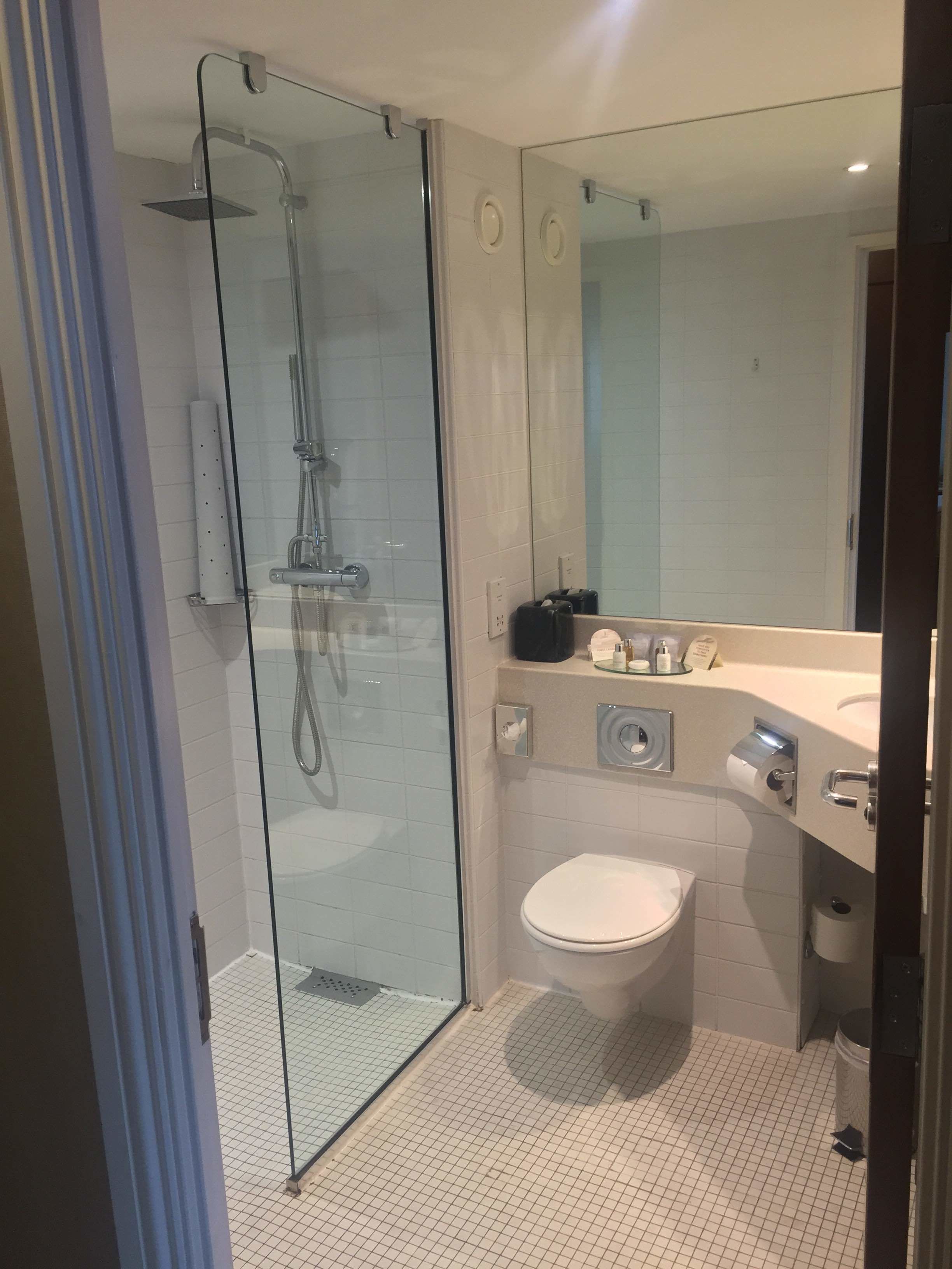Une salle de bain moderne avec une douche à parois de verre, des toilettes et un lavabo avec un miroir au-dessus.