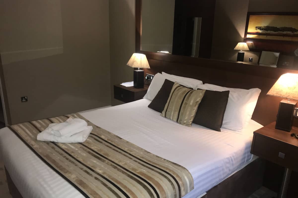 A neatly made bed with a striped blanket, two bedside lamps, and a nightstand with a lamp.
