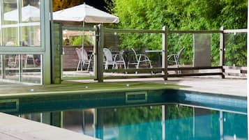 Una piscina al aire libre de temporada, sillones reclinables de piscina