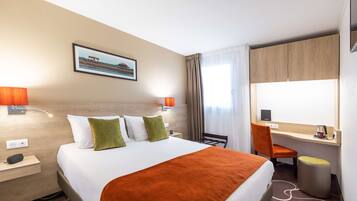 Una habitación de hotel con cama, escritorio, silla y ventana con cortinas.