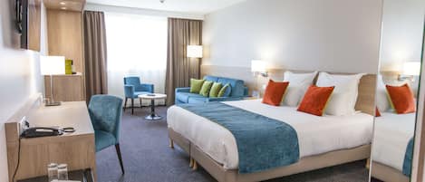 Una habitación de hotel con una cama grande, un escritorio, una silla y una mesita.