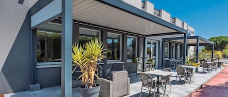 A hotel with outdoor seating and a covered patio area.
