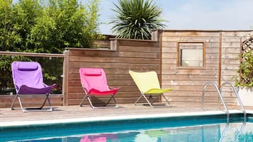 Een seizoensgebonden buitenzwembad en ligstoelen