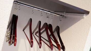 A metal rack with several pairs of shoes hanging on hooks against a wall.
