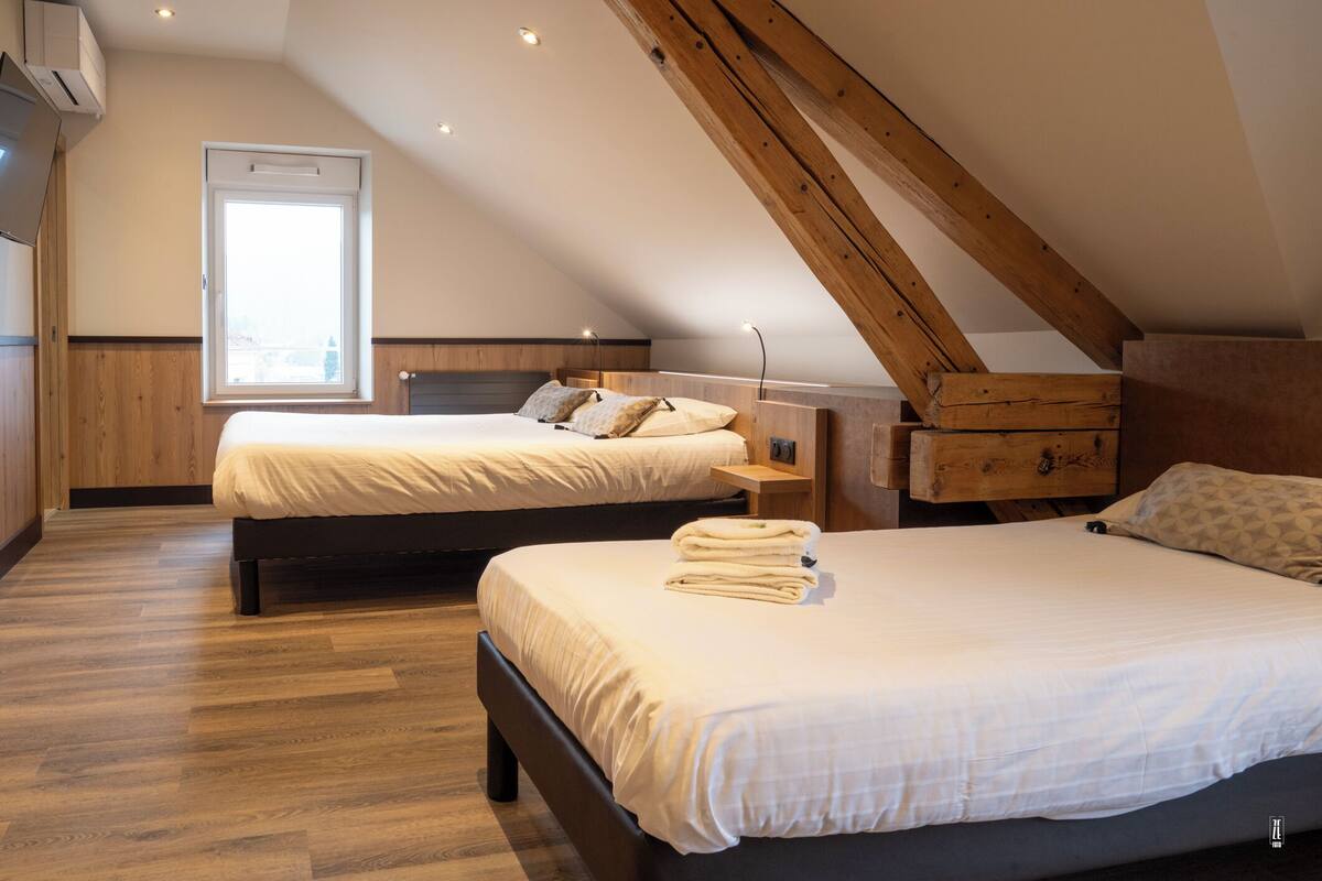 Un dormitorio con dos camas, suelo de madera, techo inclinado y una ventana.