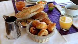 Una mesa con pan, bollería, café y zumo para el desayuno.