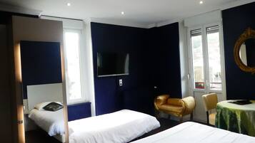 A hotel room with two beds, a TV, a chair, and a table.