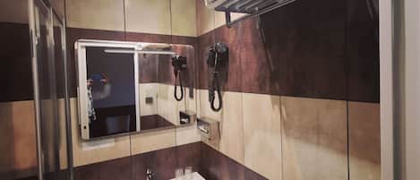 Un baño con espejo, lavamanos, toallero y secador de pelo.