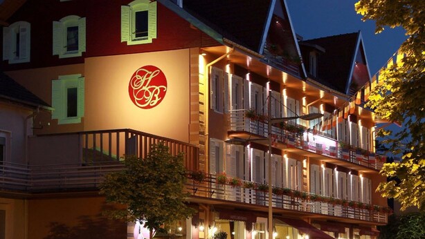Un hotel con un logotipo destacado, varios balcones y una fachada bien iluminada.