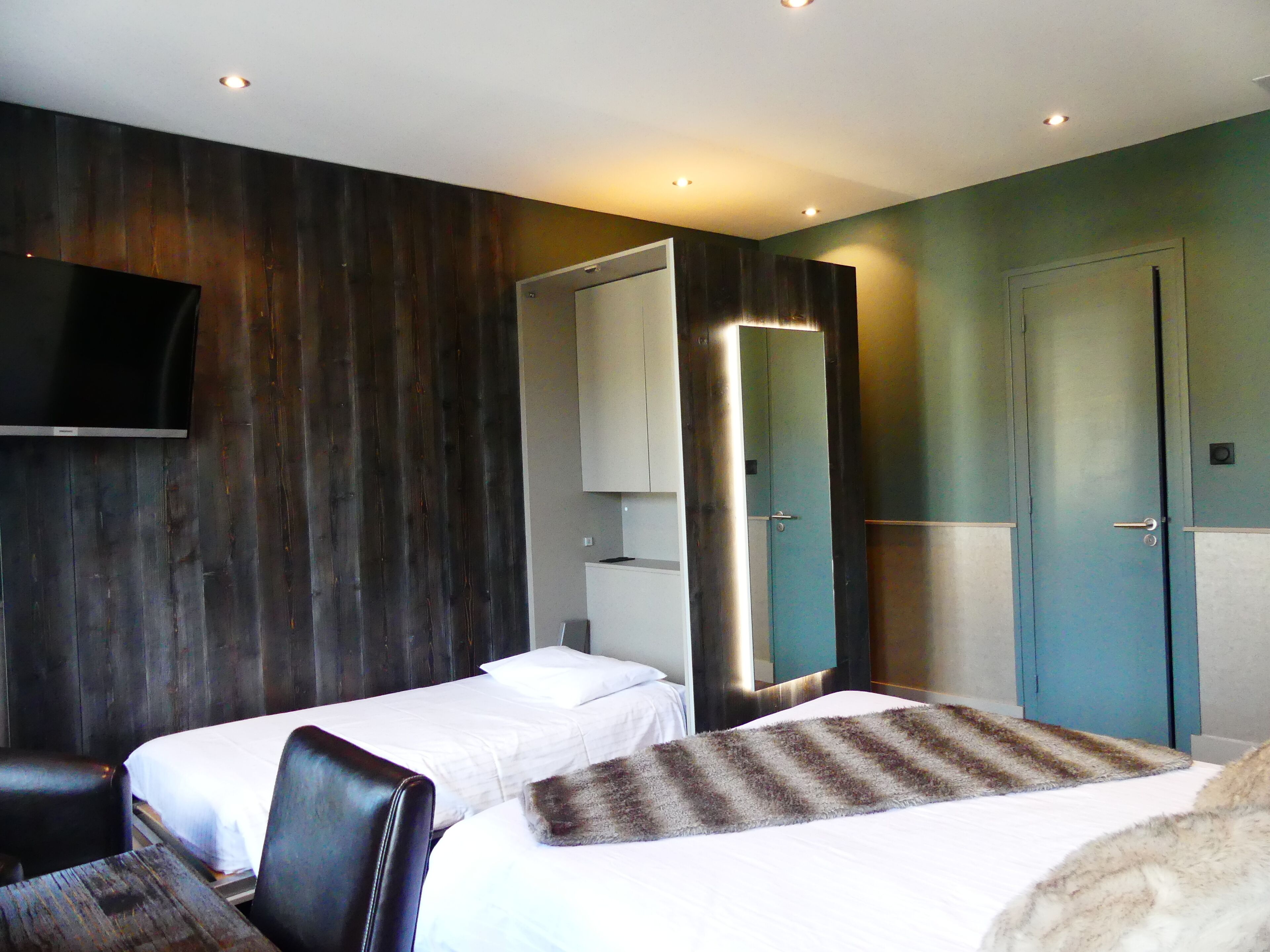 Una habitación de hotel con dos camas, un televisor, un espejo y una puerta.