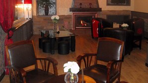 Un área de descanso acogedora con chimenea, asientos cómodos y un jarrón con flores sobre una mesa.