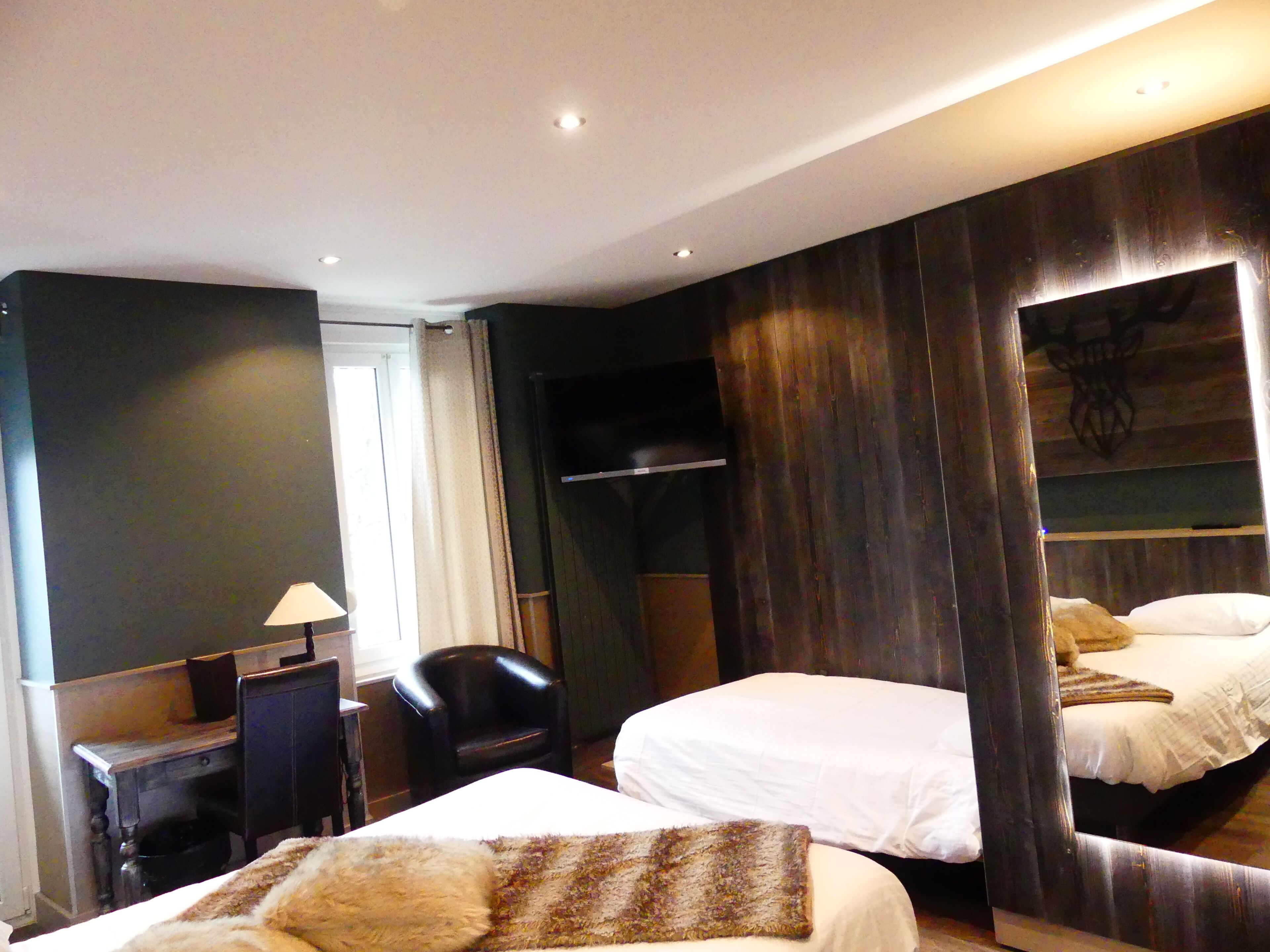 A hotel room with two beds, a desk, a chair, and a wardrobe.
