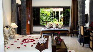 A hotel room with a bed, a desk, a chair, and a window with a view of greenery. - White House Beach Resort (Koh Samui)