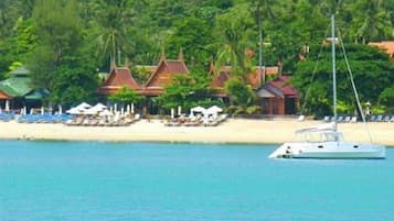 Na praia, areia branca, espreguiçadeiras, guarda-sóis