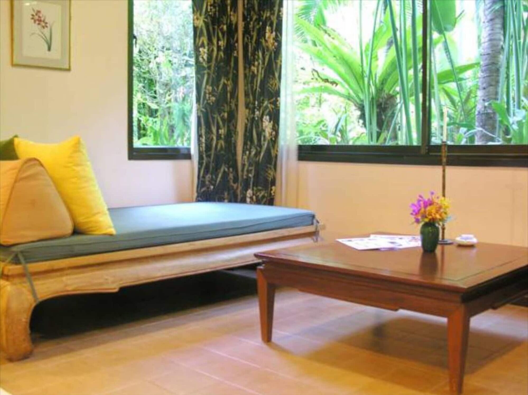 Una habitación con un banco de madera, una mesita con un jarrón de flores y una ventana que da a vistas de follaje.