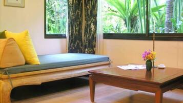 Una habitación con un banco de madera, una mesita con un jarrón de flores y una ventana que da a vistas de follaje.