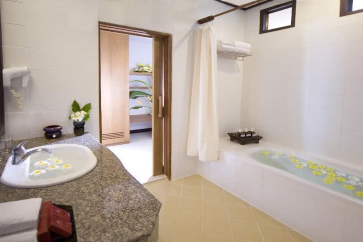 A bathroom with a sink, bathtub, and shower curtain.