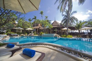 Una piscina al aire libre, sombrillas, sillones reclinables de piscina
