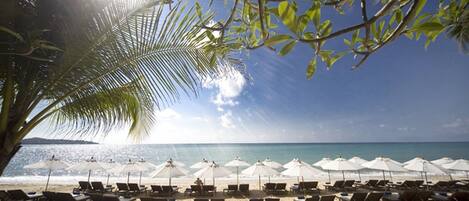 A beach with sun umbrellas and lounge chairs.