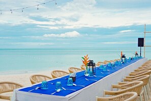 A beachside dining setup with wicker chairs and a long table, overlooking the ocean. - The Fair House Beach Resort & Hotel (Koh Samui)