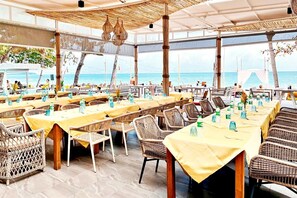 An outdoor dining area with tables and wicker chairs, overlooking the sea. - The Fair House Beach Resort & Hotel (Koh Samui)