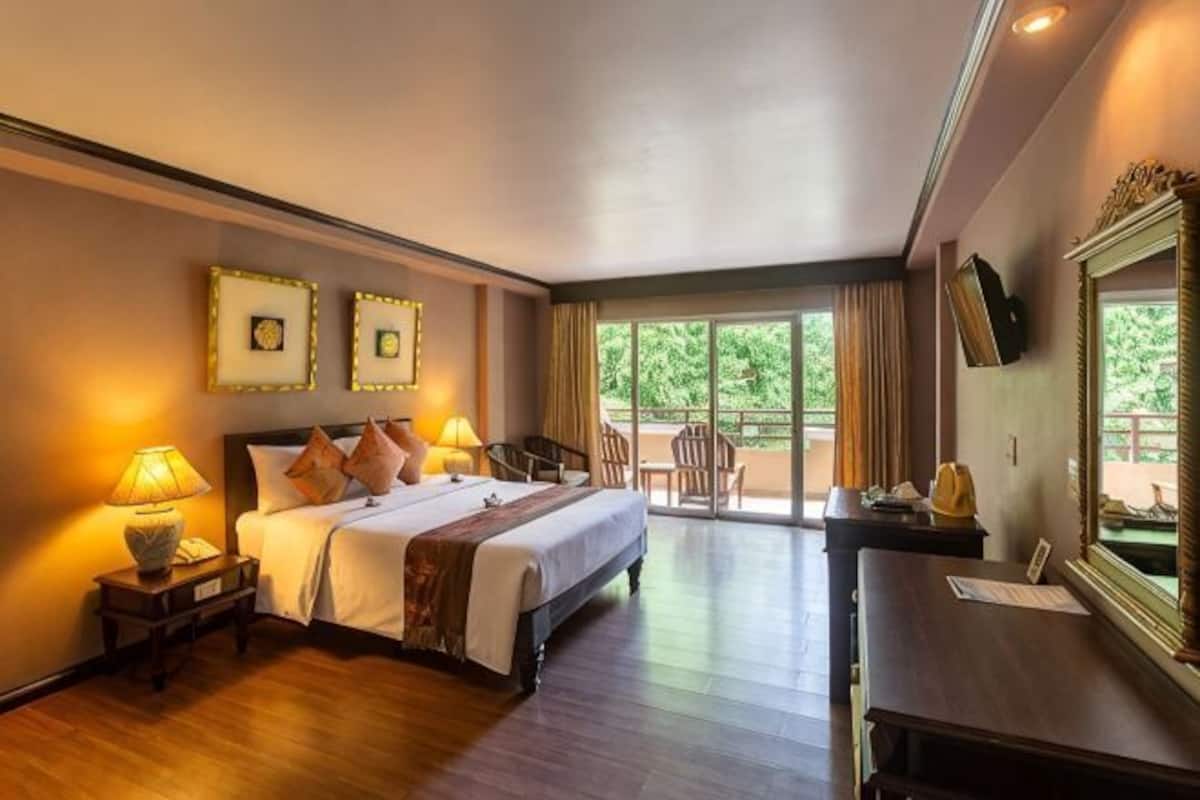 Una habitación de hotel con cama, lámparas de noche, escritorio, silla y televisor.