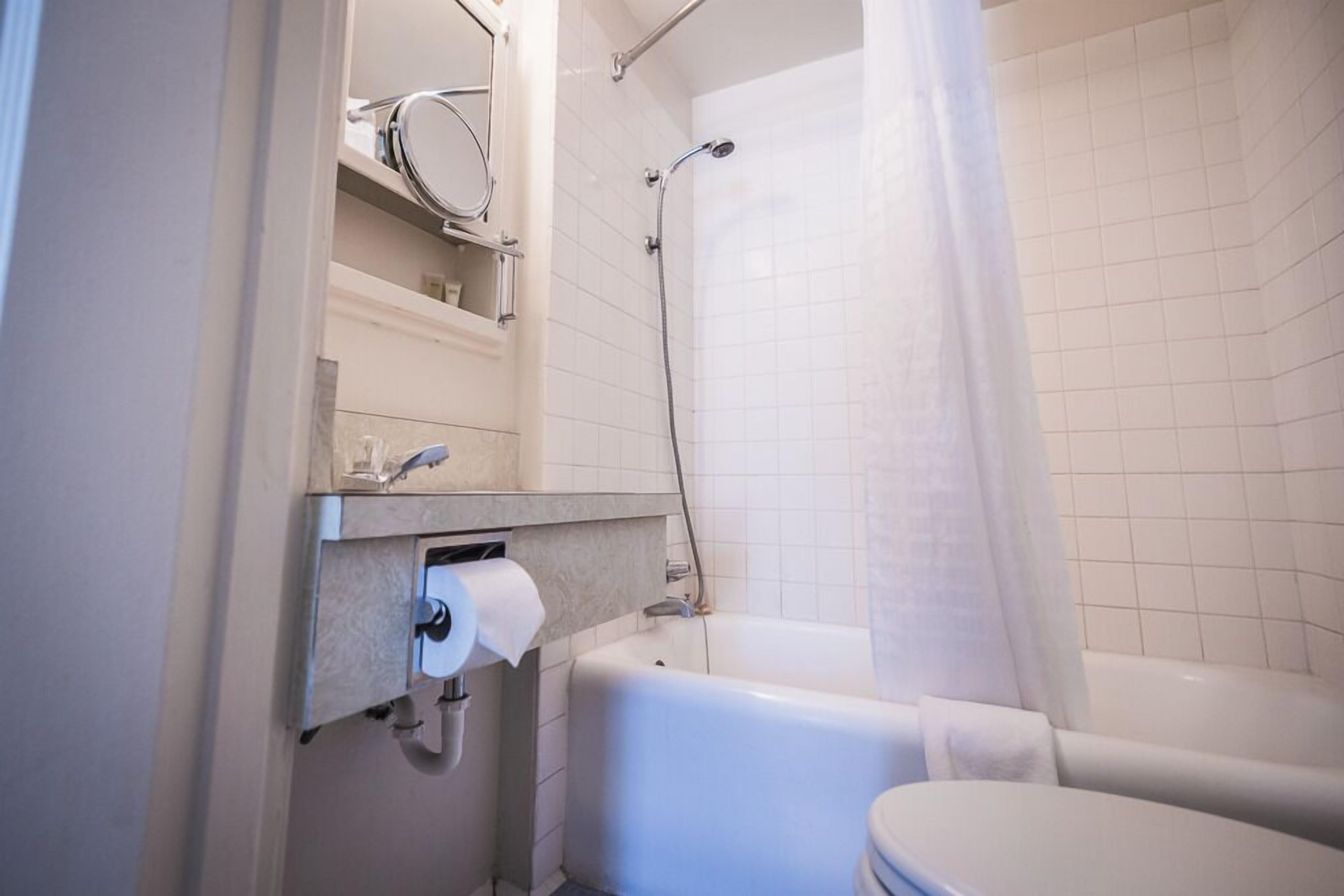 A bathroom with a toilet, a bathtub, a shower, and a mirror.