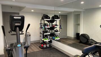 A modern gym with a stationary bike, a treadmill, and a mirrored wall reflecting the equipment.