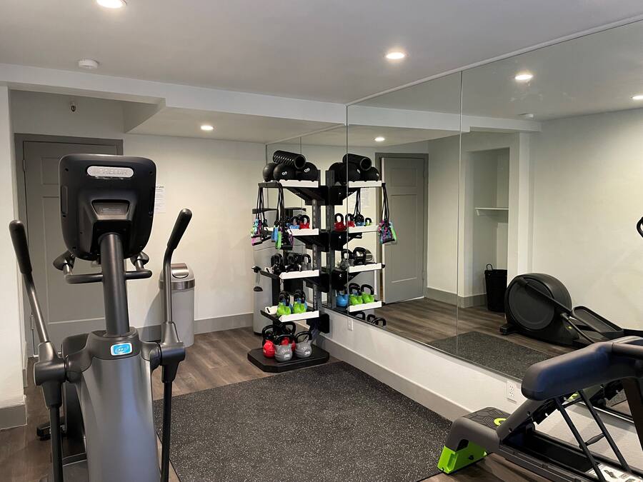 A modern gym with a stationary bike, a treadmill, and a mirrored wall reflecting the equipment.