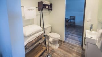 A compact bathroom with a toilet, a sink, and a small bed area.