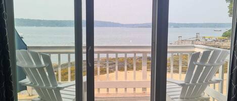 A room with a view of a beach and the sea through large sliding glass doors.