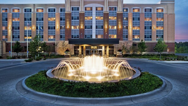 A Sheraton hotel with a central fountain, large windows, and a brick facade. - Sheraton St. Paul Woodbury Hotel (Woodbury)