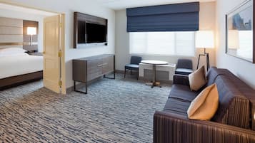 Una habitación de hotel con cama, escritorio, sofá, televisión y ventana con vistas.