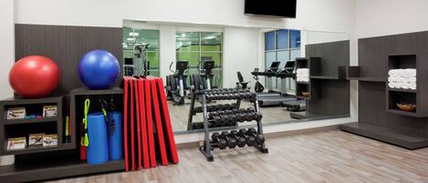 A gym with exercise equipment, a mirror, and a television.