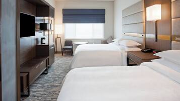 A hotel room with two beds, a TV, a desk, and a chair.