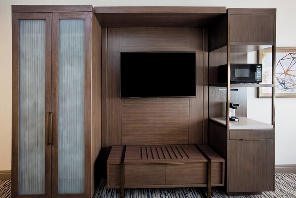 A compact room with a built-in TV, a microwave, and a small seating area. - Sheraton St. Paul Woodbury Hotel (Woodbury)