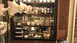 Una zona de bar con diversas botellas de licor, una mesa de buffet y un panel de madera.
