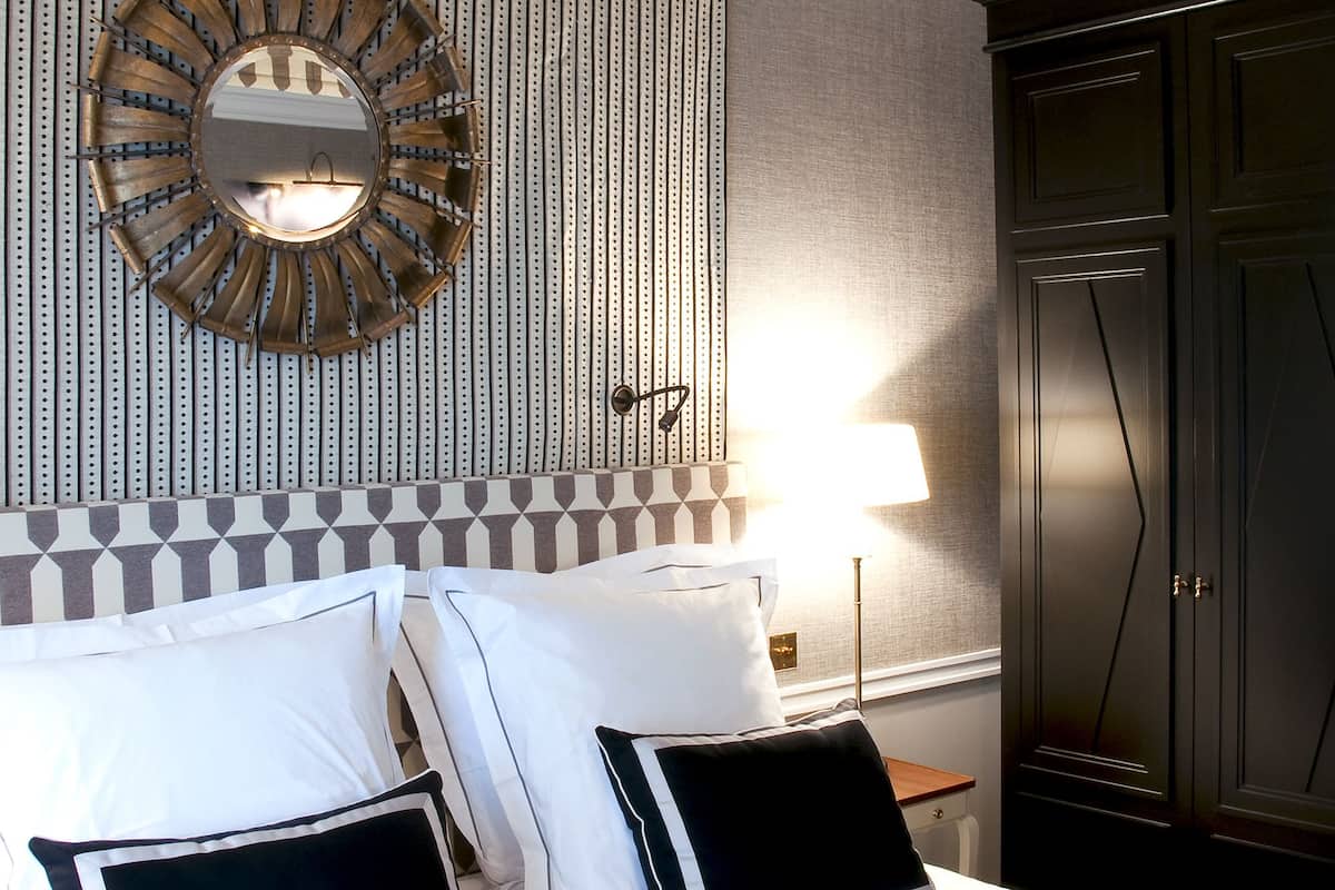 Une chambre d’hôtel avec un lit, un miroir, une lampe et une armoire.