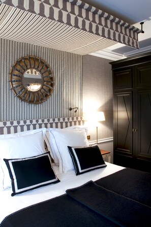 A hotel room with a bed, a mirror, a lamp, and a wardrobe.
