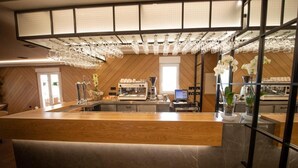 Una zona de bar moderna con mostrador de madera, una máquina de café y un expositor de vidrio.