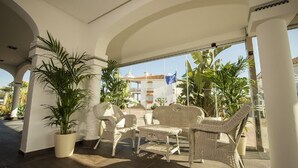 Un área de estar al aire libre cubierta con muebles de mimbre y plantas en macetas.