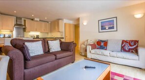 A living room with a brown sofa and a white sofa, a coffee table, and a kitchen in the background. - London Tower Bridge Apartments (London)